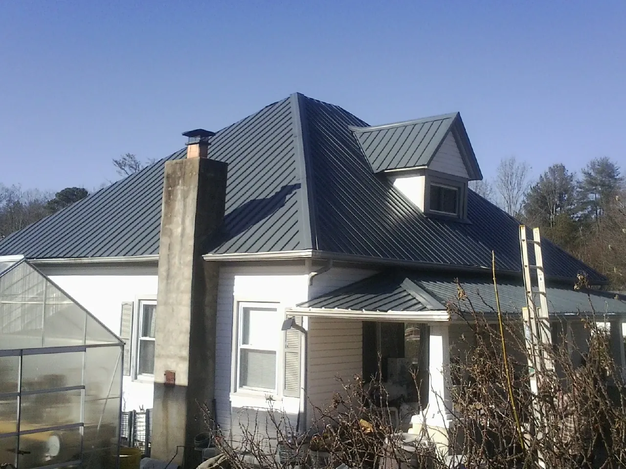 Dark blue standing seam metal roof on a white farmhouse with dormer — Slate & Tile Roof Repair by Roofing Brothers in Crossnore