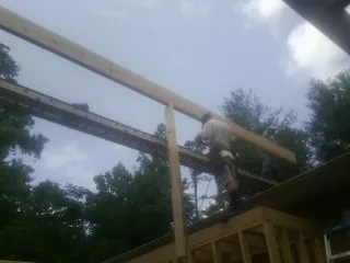 Carpenter setting a ridge beam over a new addition frame — Ice Dam Removal by Roofing Brothers in Crossnore