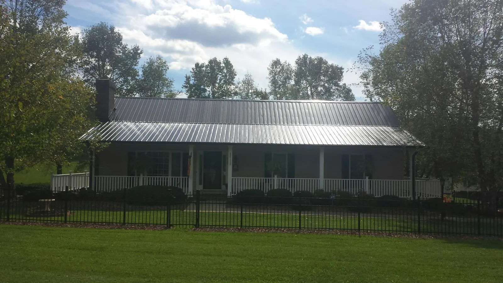 Gray metal roof on a brick ranch with a full width front porch — Gutter Guard Installation work by our crew in Crossnore