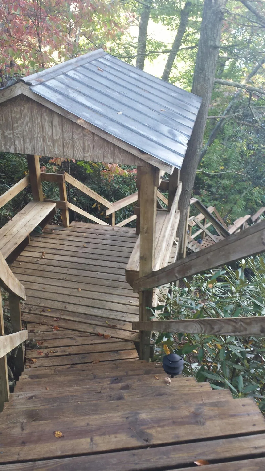 Metal roofed shelter over wooden steps on a wooded walkway — Skylight Repair & Installation work by our crew in Crossnore
