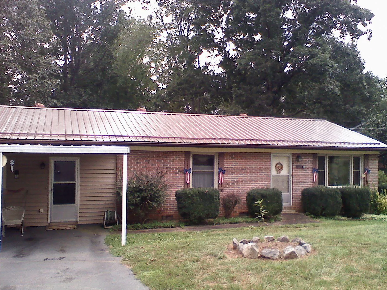 Bronze metal roof and carport on a brick ranch home — Roof Repair work by our crew in Crossnore