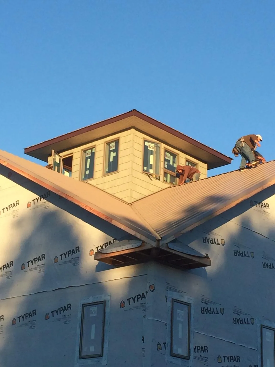 Roofers working around a rooftop cupola on a new metal roof at sunset — Roof Waterproofing in Crossnore by Roofing Brothers
